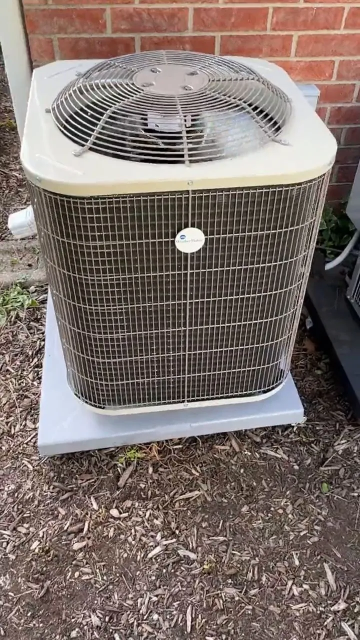 A newly installed outdoor condensing unit on a pad beside a brick wall.