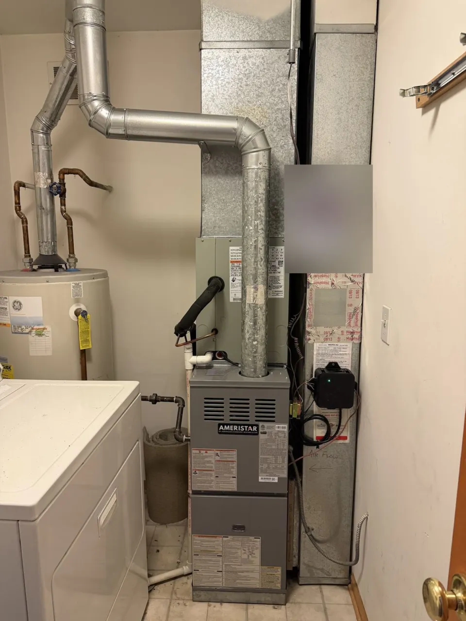 A new gas furnace and evaporator coil in the same laundry closet after replacement, venting reworked.