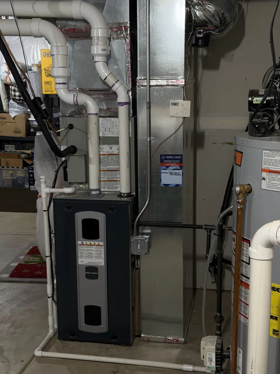 A high-efficiency furnace in a basement with its PVC intake and exhaust piping run to the wall.