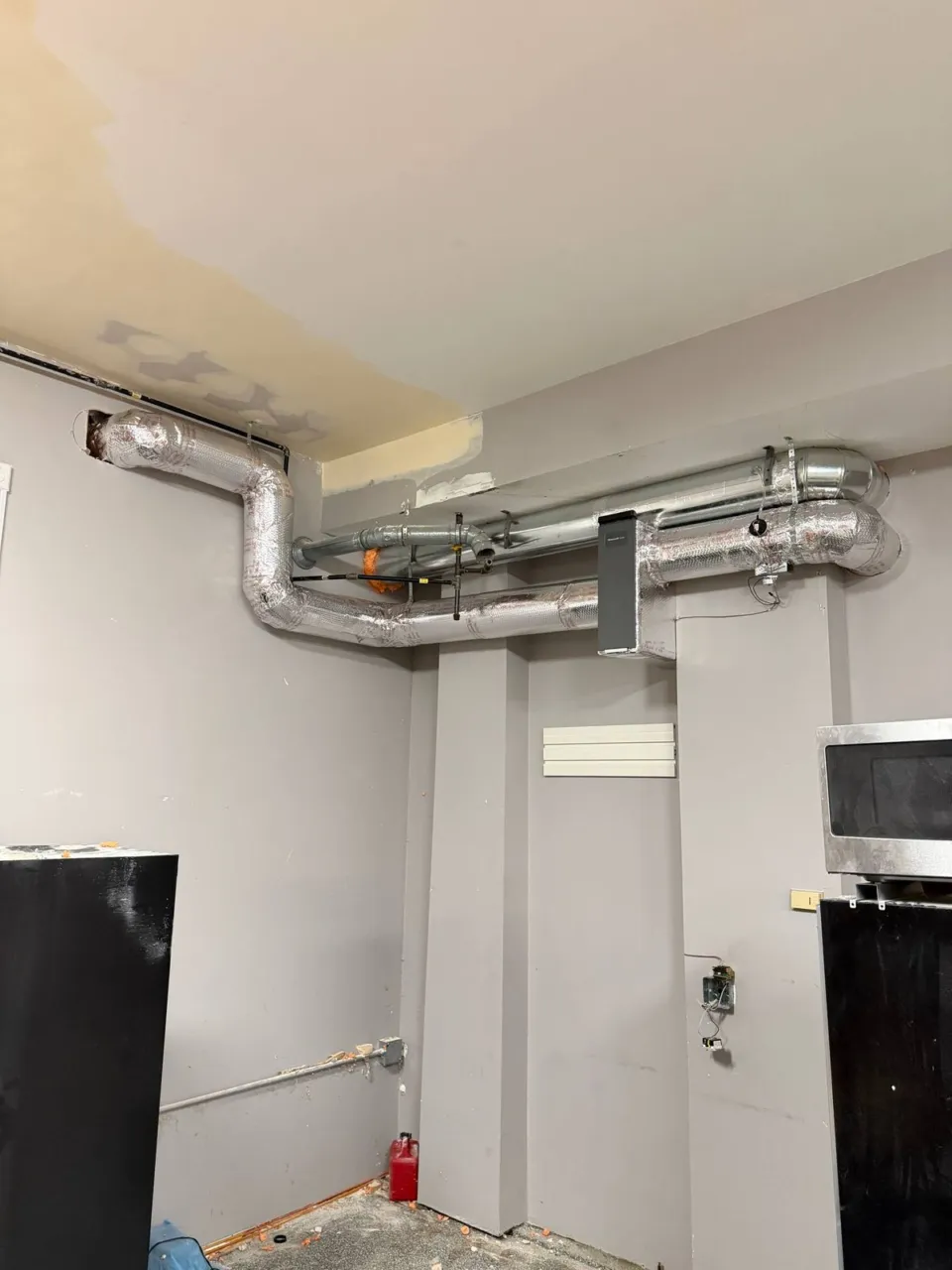 Make-up air duct with a balancing damper running along a garage ceiling to the filter section.