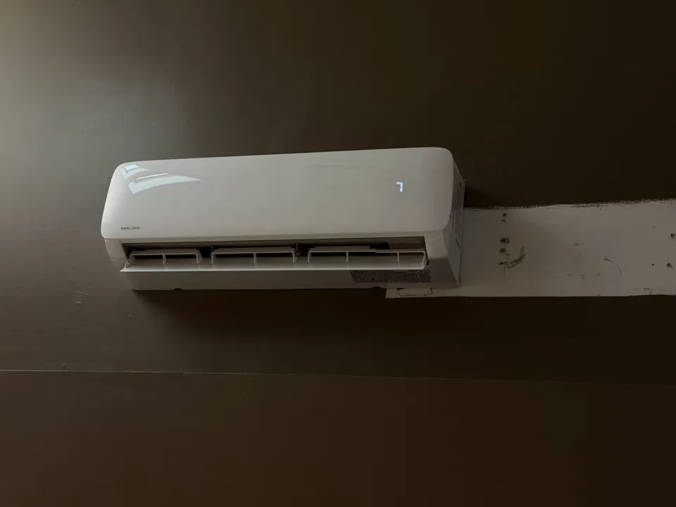 A MrCool wall-mounted indoor unit on a dark wall, next to a strip of unpainted wall.