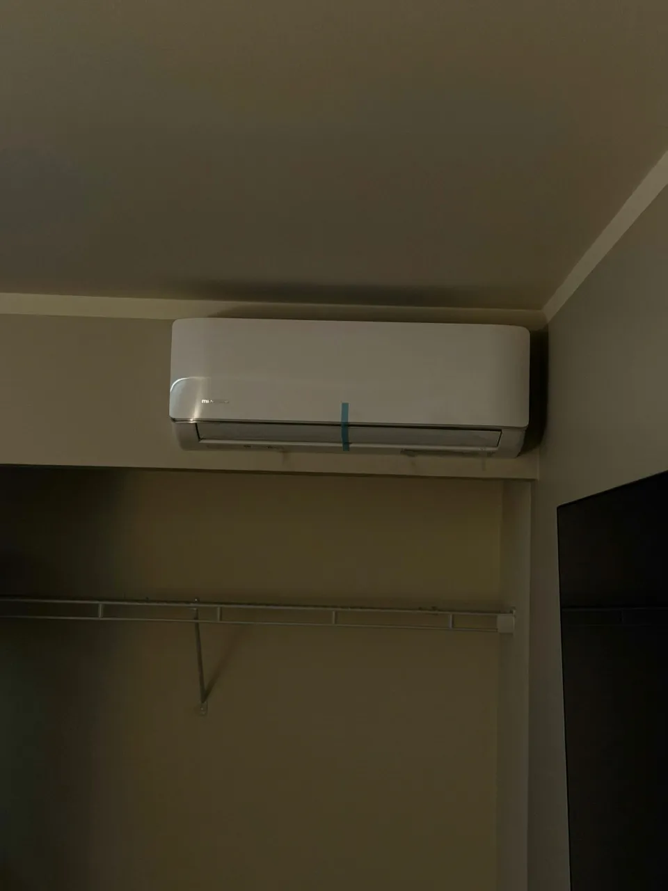The second indoor head of the same system, mounted above a closet opening with the empty hanging rail below it.