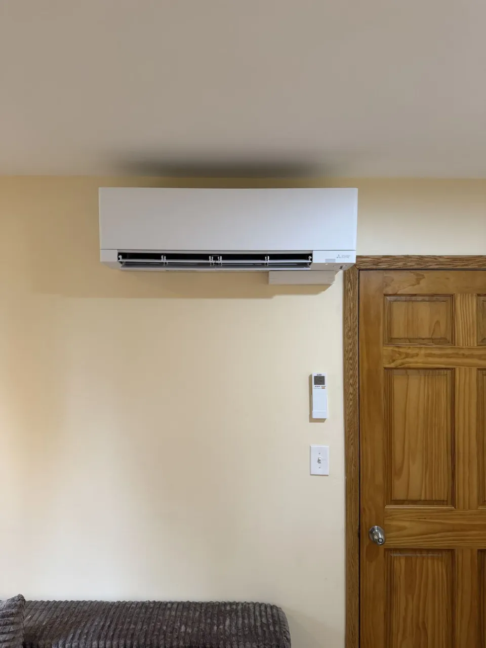 A wall-mounted ductless indoor head installed above a doorway, with the remote holder on the wall beside it.