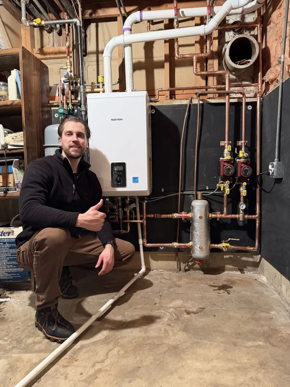 Wall-mounted Navien boiler with copper piping and circulator pumps.