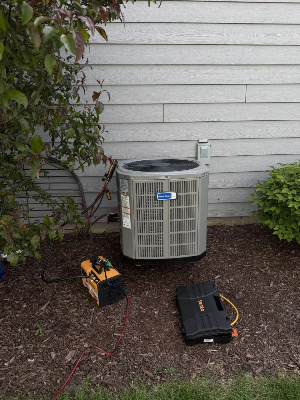 The replacement American Standard outdoor air conditioner beside the house.
